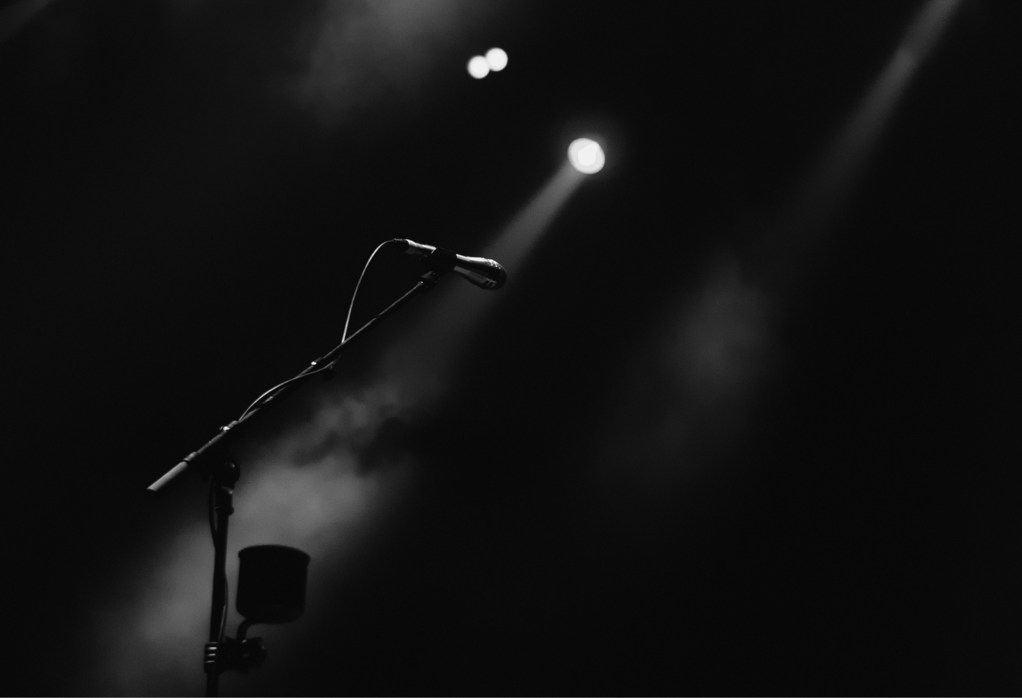 A picture of an empty, dark stage with a microphone and lights
