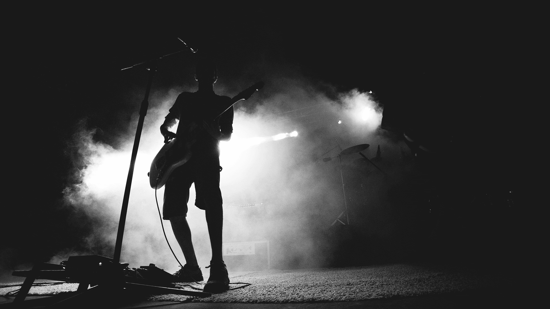 a photo of a man performing on stage playing guitar and singing
